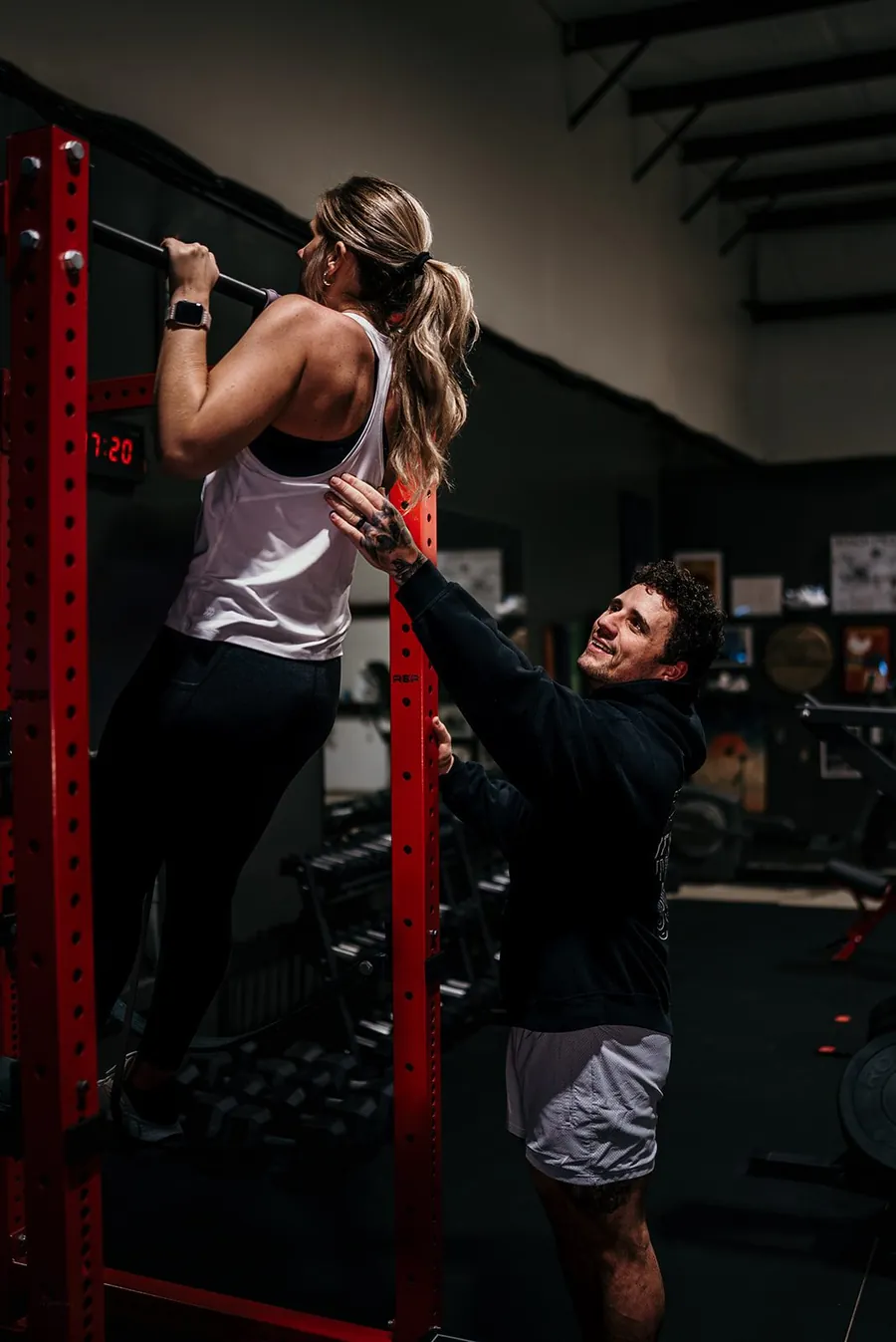 Coach spotting a client during a pull-up at Anew Training in Dover, DE